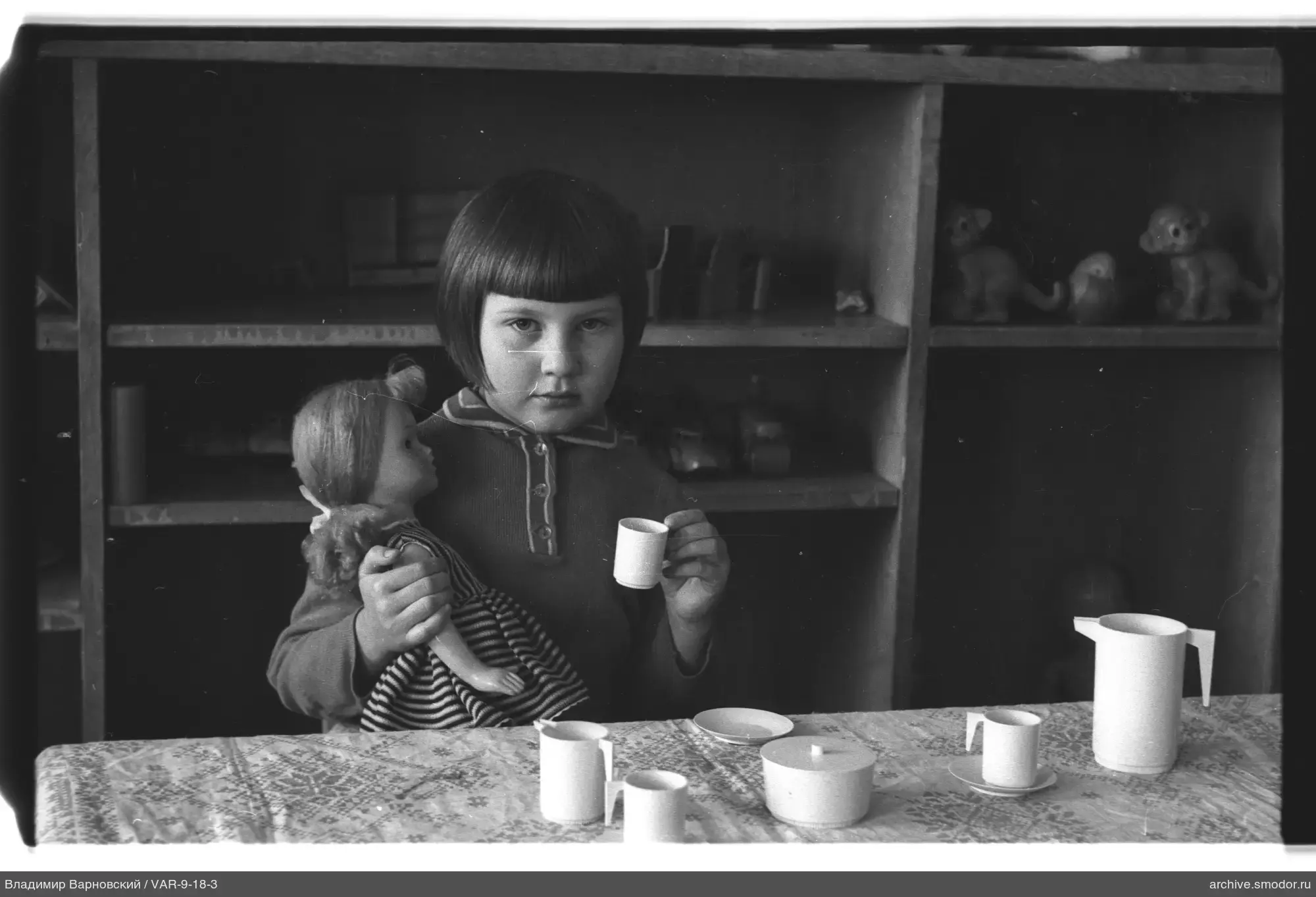 Mädchen mit Puppe und Teeservice