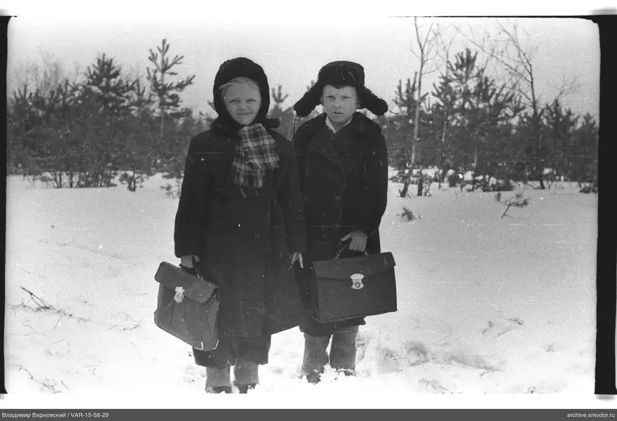 Zwei Kinder im Schnee mit Schultaschen
