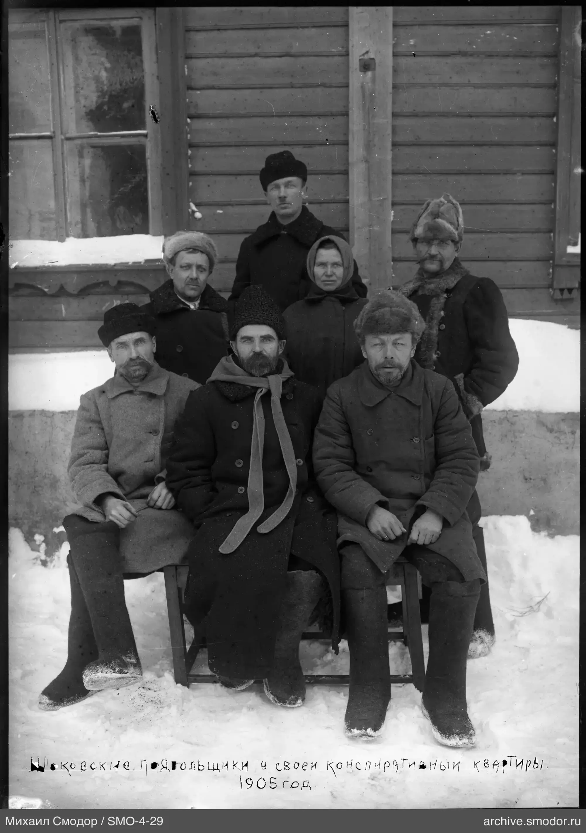 Gruppe von Menschen bei einem Holzhaus im Schnee