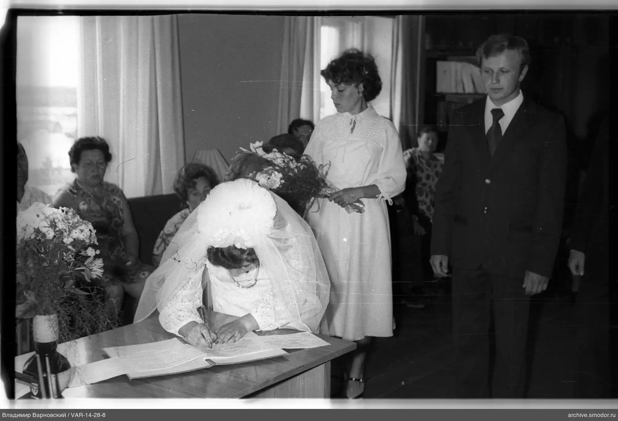 Женщина в белом платье подписывает документ