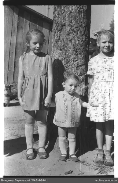 Gruppe von Kindern bei Baum und Holzgebäude