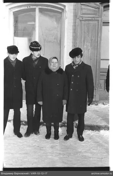 Gruppe von Menschen im Schnee vor einem Ziegelgebäude