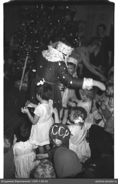 Frau mit Kindern vor geschmücktem Weihnachtsbaum
