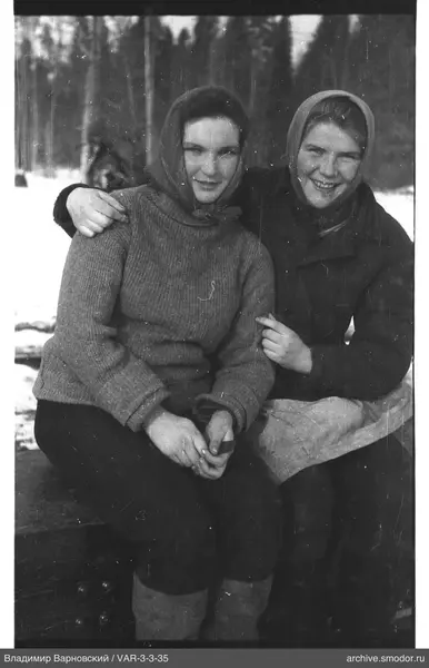 Two women sitting on a bench in winter park
