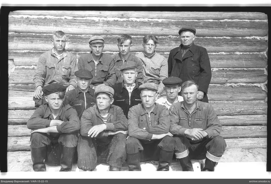 Gruppe von Männern und Jungen vor Holzhaus