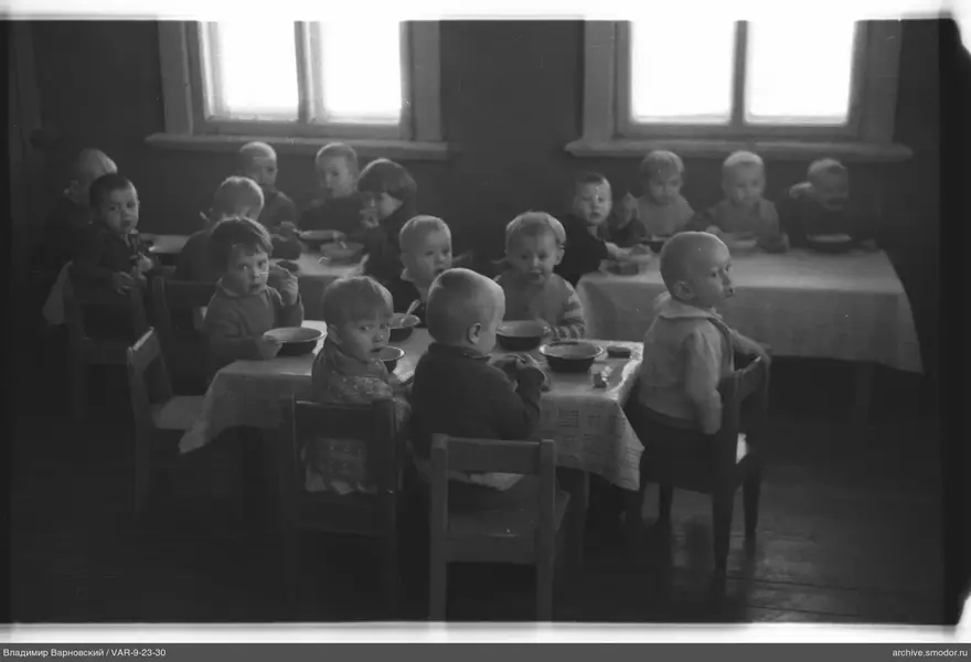 Children sitting at tables with bowls and spoons