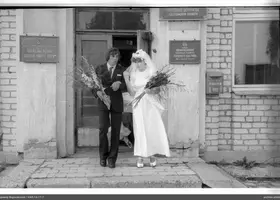 Woman with bouquet and man exiting building