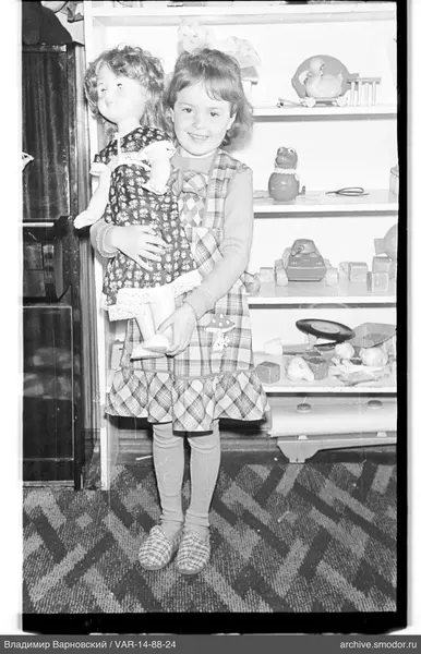 Child with large doll and toys on shelf