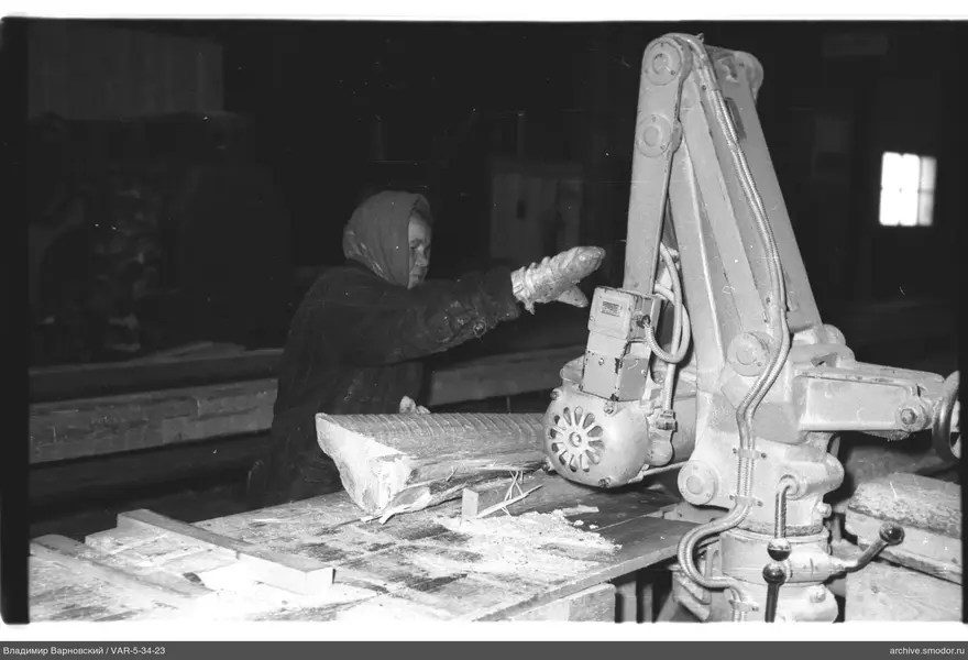 Frau an Maschine mit Holzbalken