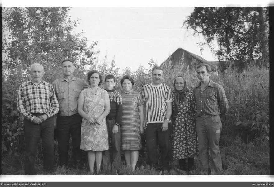 Gruppe von Menschen vor Büschen und Haus