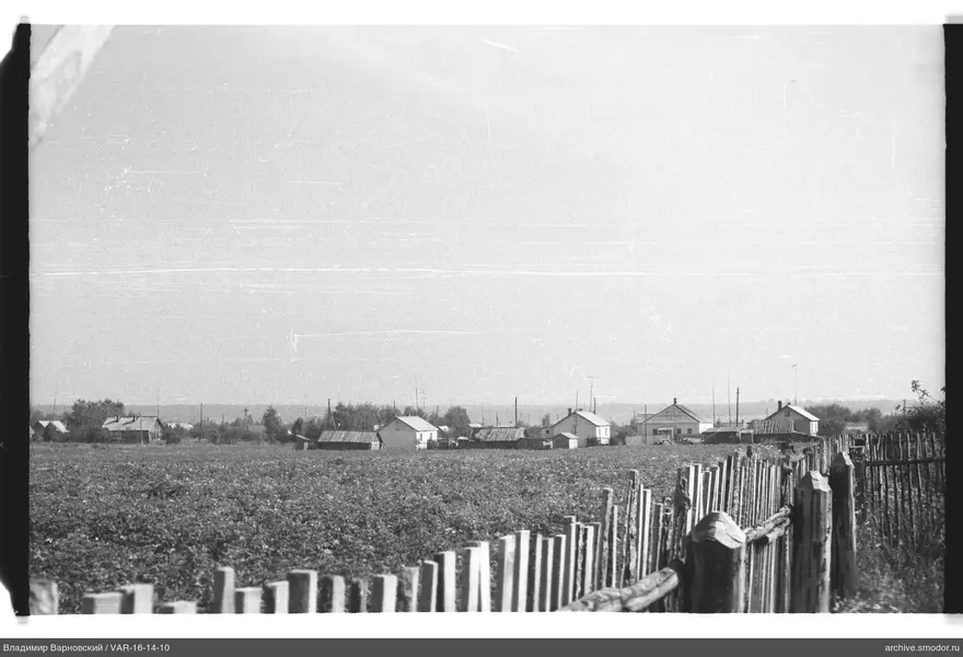 Landschaft mit Feld, Zaun und Häusern