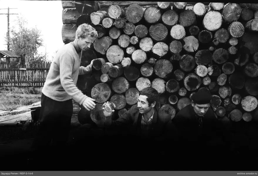 Gruppe von Männern vor Holzstapel