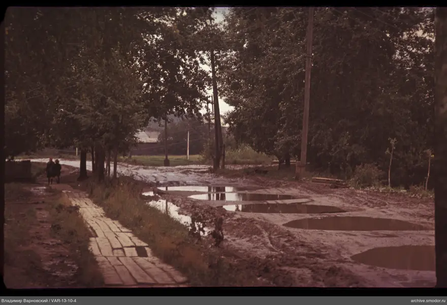 Dirt road with trees and wooden buildings