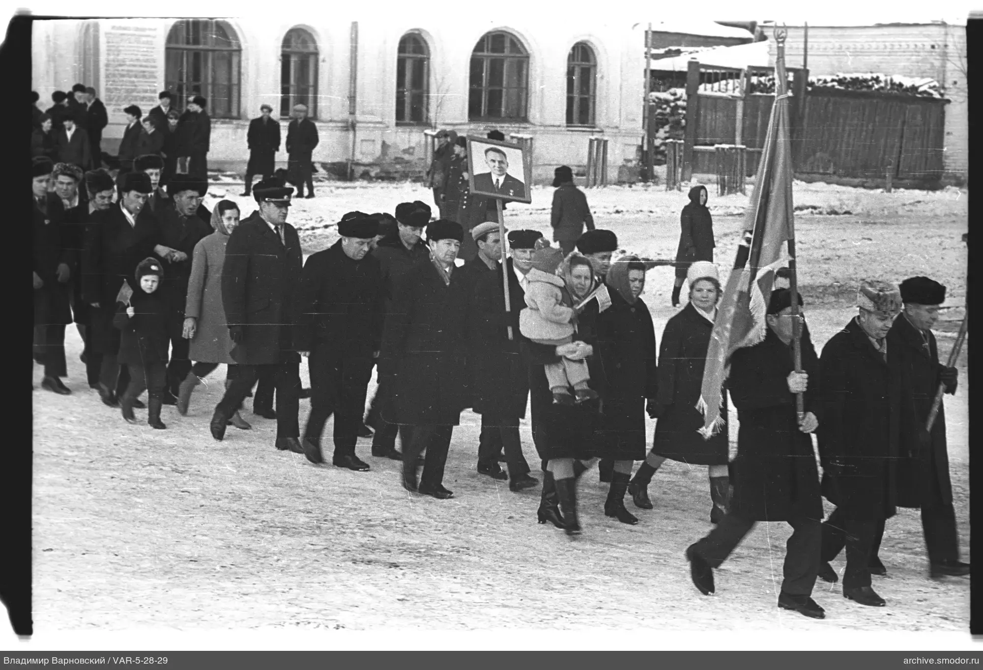 Группа людей на зимней улице с флагами и портретом