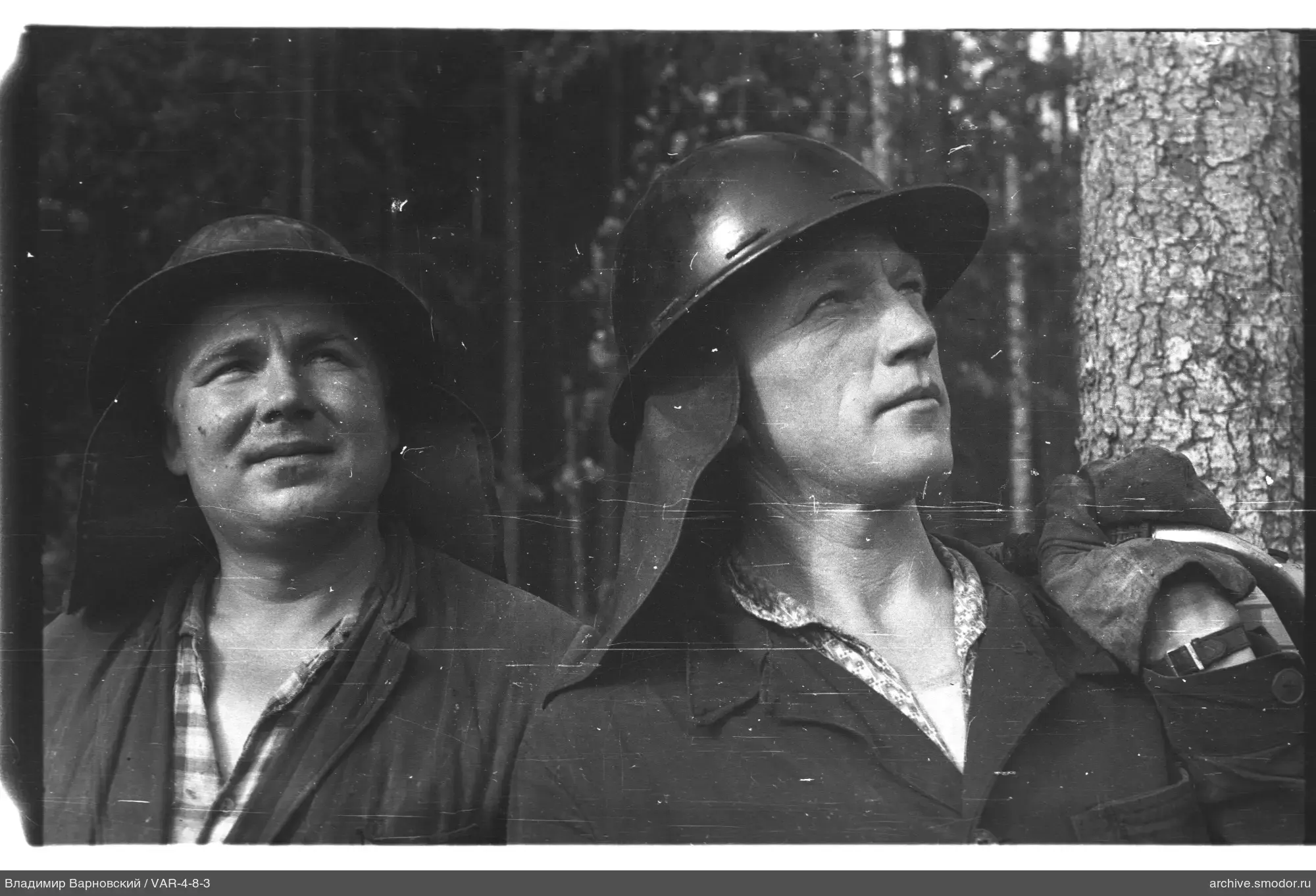 Zwei Männer mit Helmen vor einem Wald