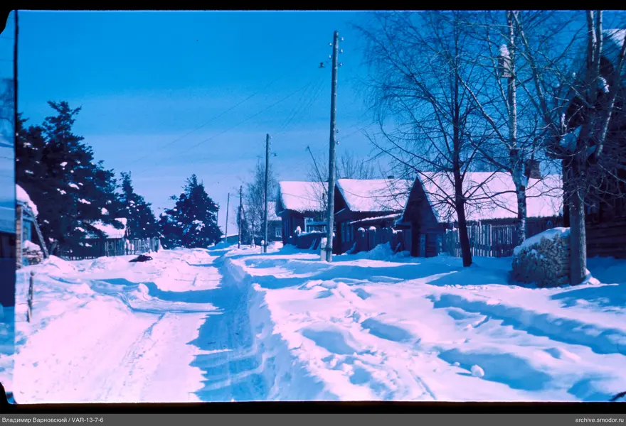 Snow-covered street with wooden houses