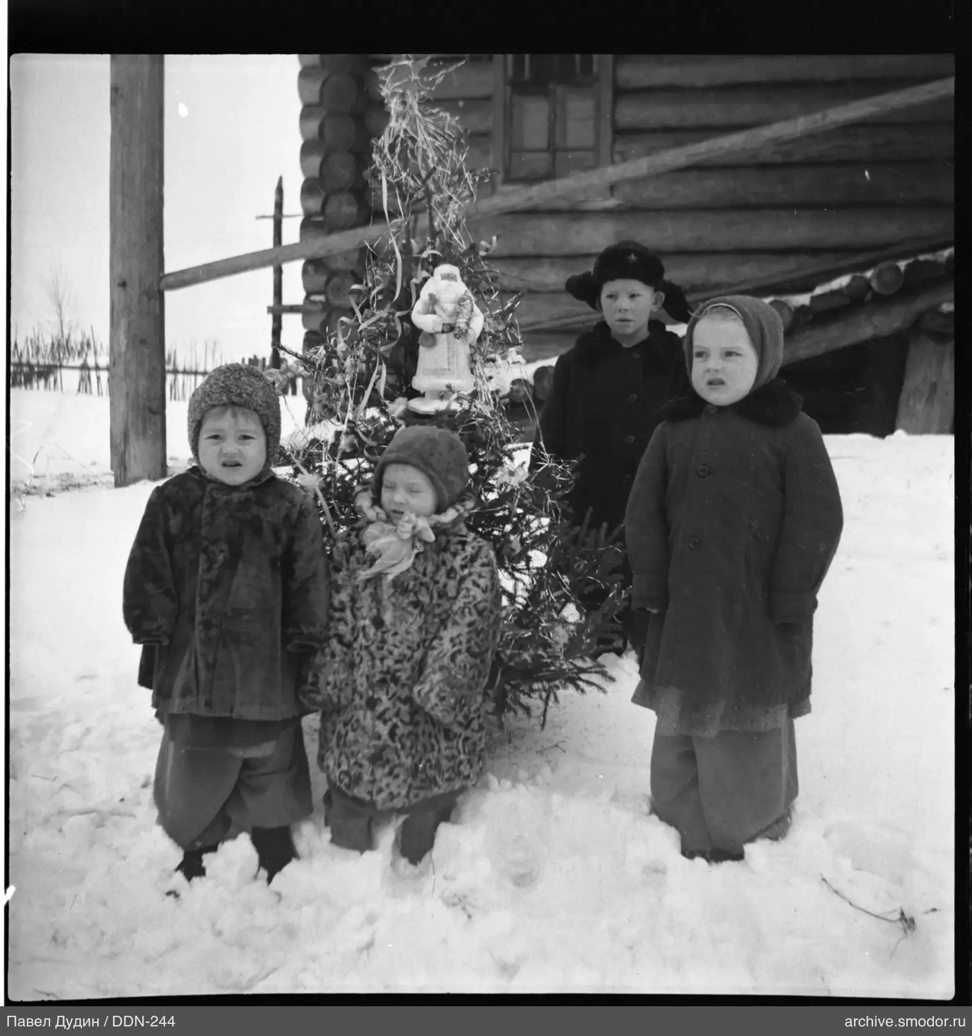 Children in winter clothing with Christmas tree
