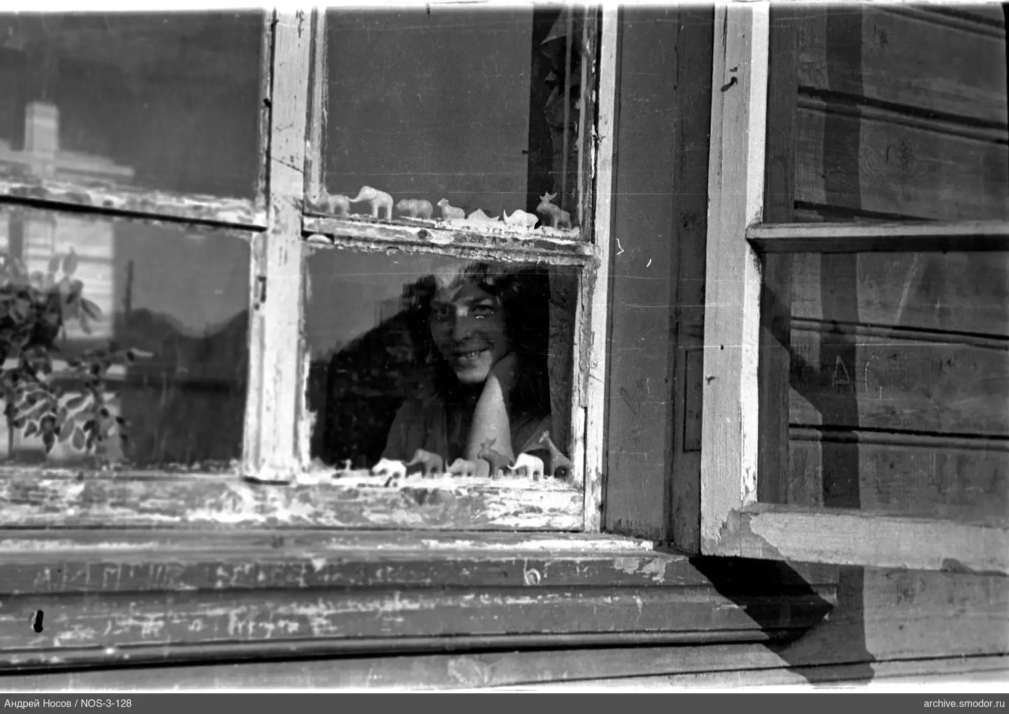 Frau hinter altem Holzfenster mit Figuren