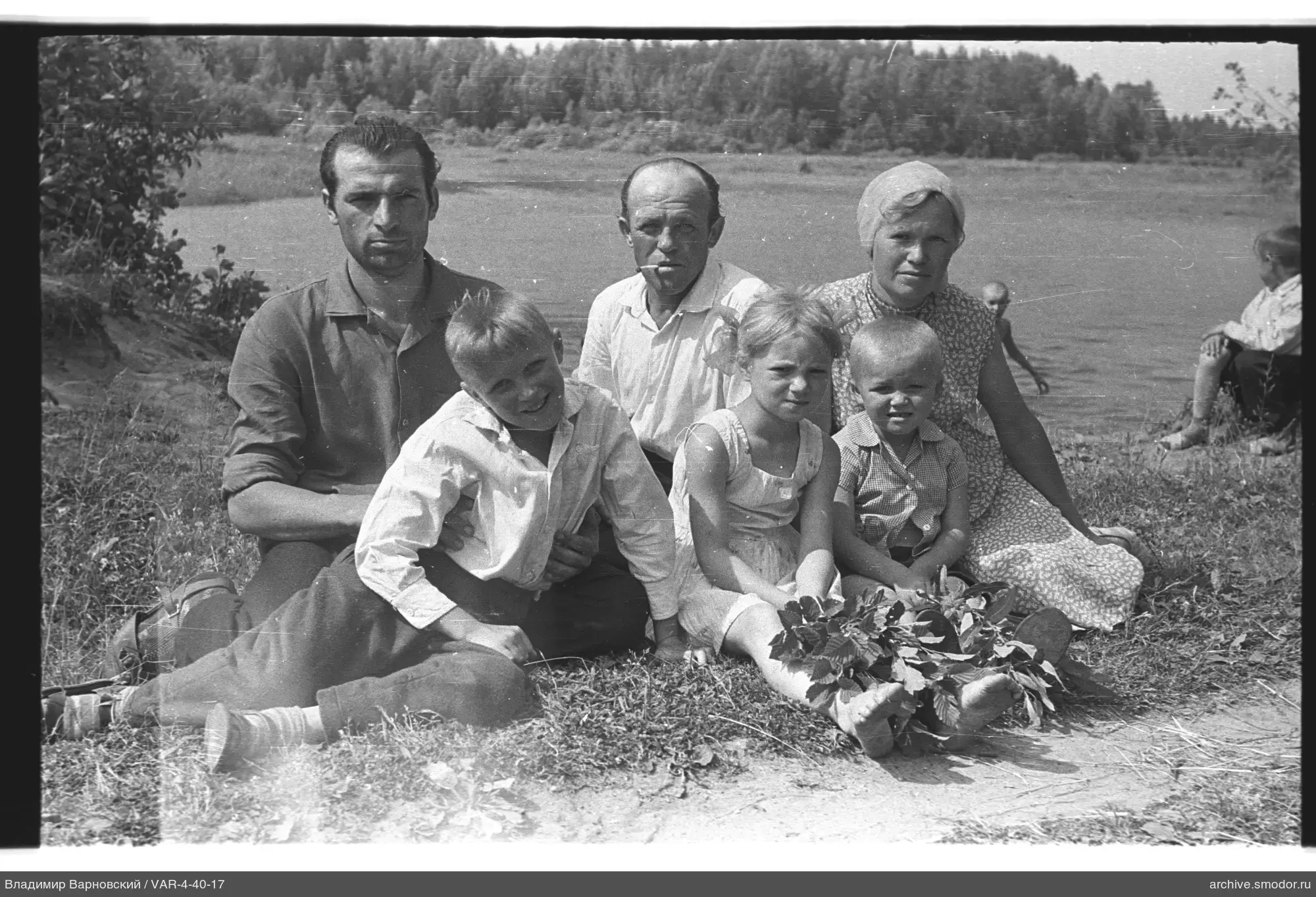 Группа людей на траве с водоемом