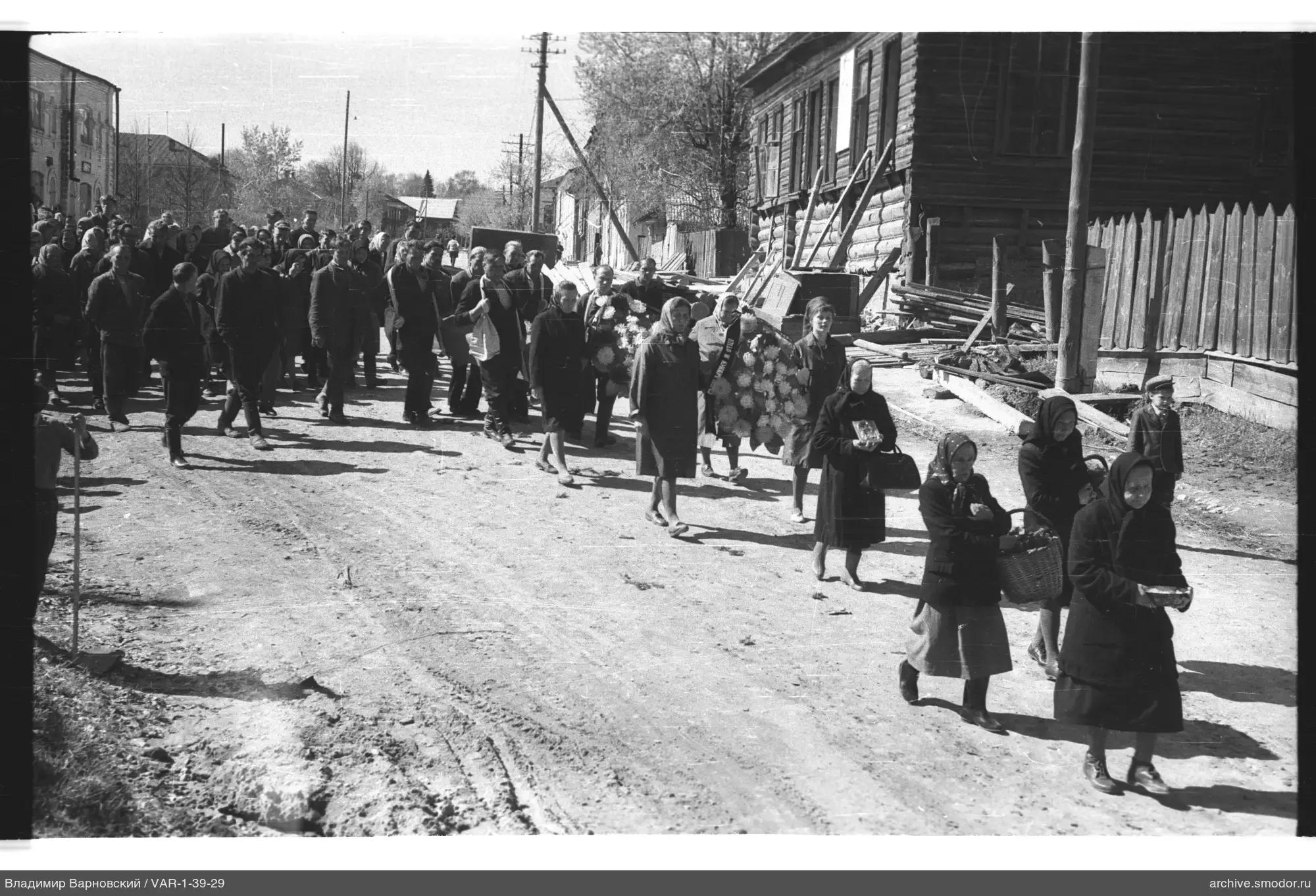 Gruppe von Menschen mit Kränzen und Korb auf Straße