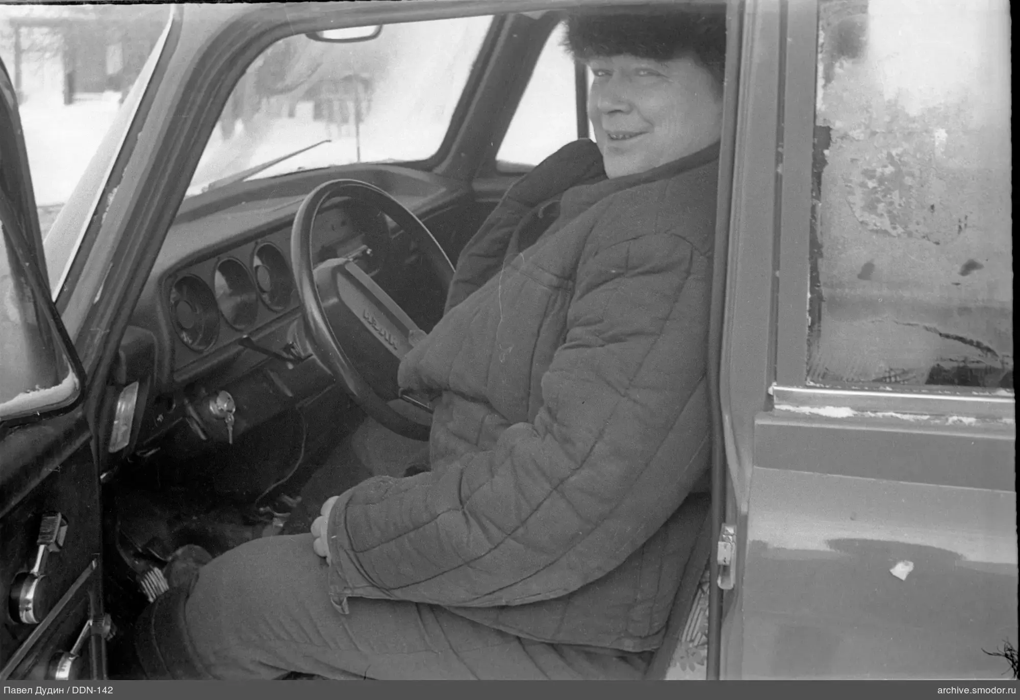 Мужчина в меховой шапке за рулём автомобиля