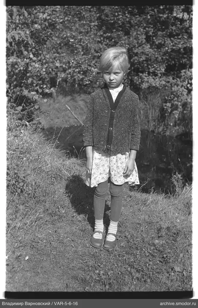 Mädchen am Wasser in Kleid und Strickjacke