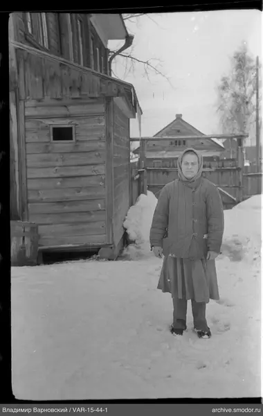 Женщина у деревянного дома на снегу