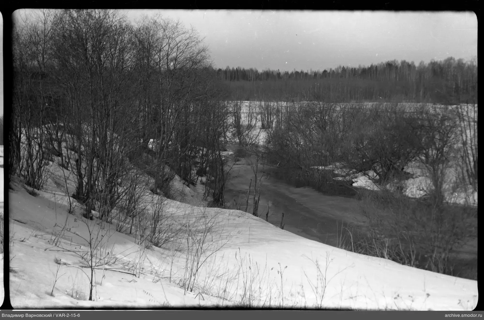 Schneebedeckter Hang mit Fluss und Wald