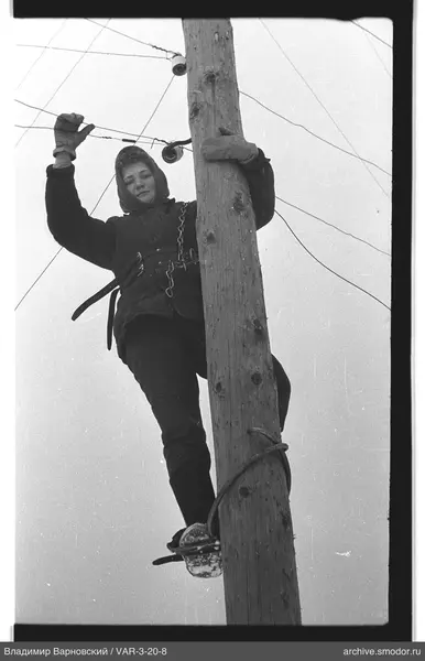 Person climbing a wooden pole with wires