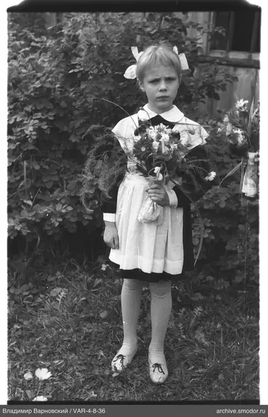 Mädchen mit Blumenstrauß vor Büschen