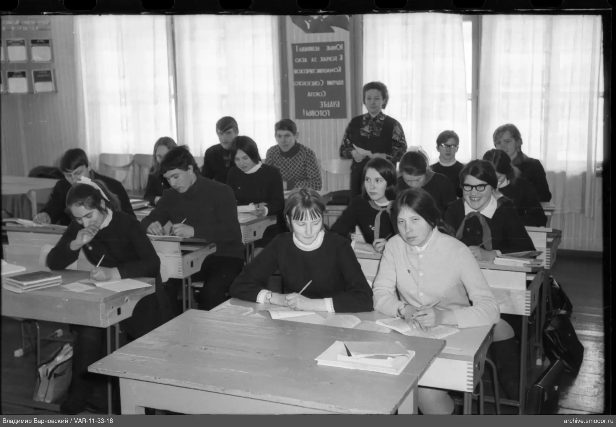 Ученики в классе и женщина с бумагой