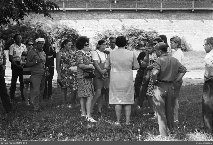 Gruppe von Menschen vor Ziegelmauer im Gras