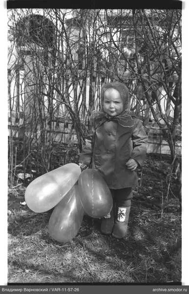 Kind mit Ballons bei Büschen