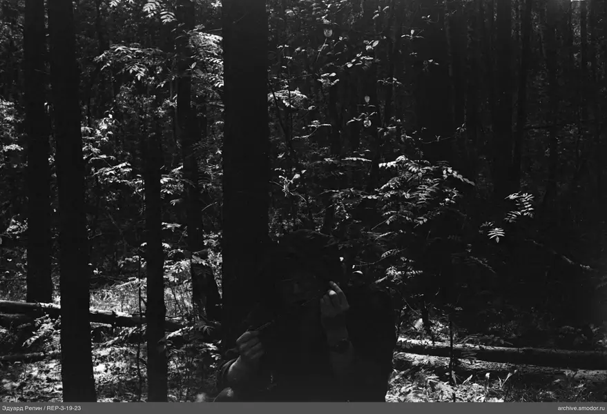 Person im Wald mit Gegenständen in den Händen