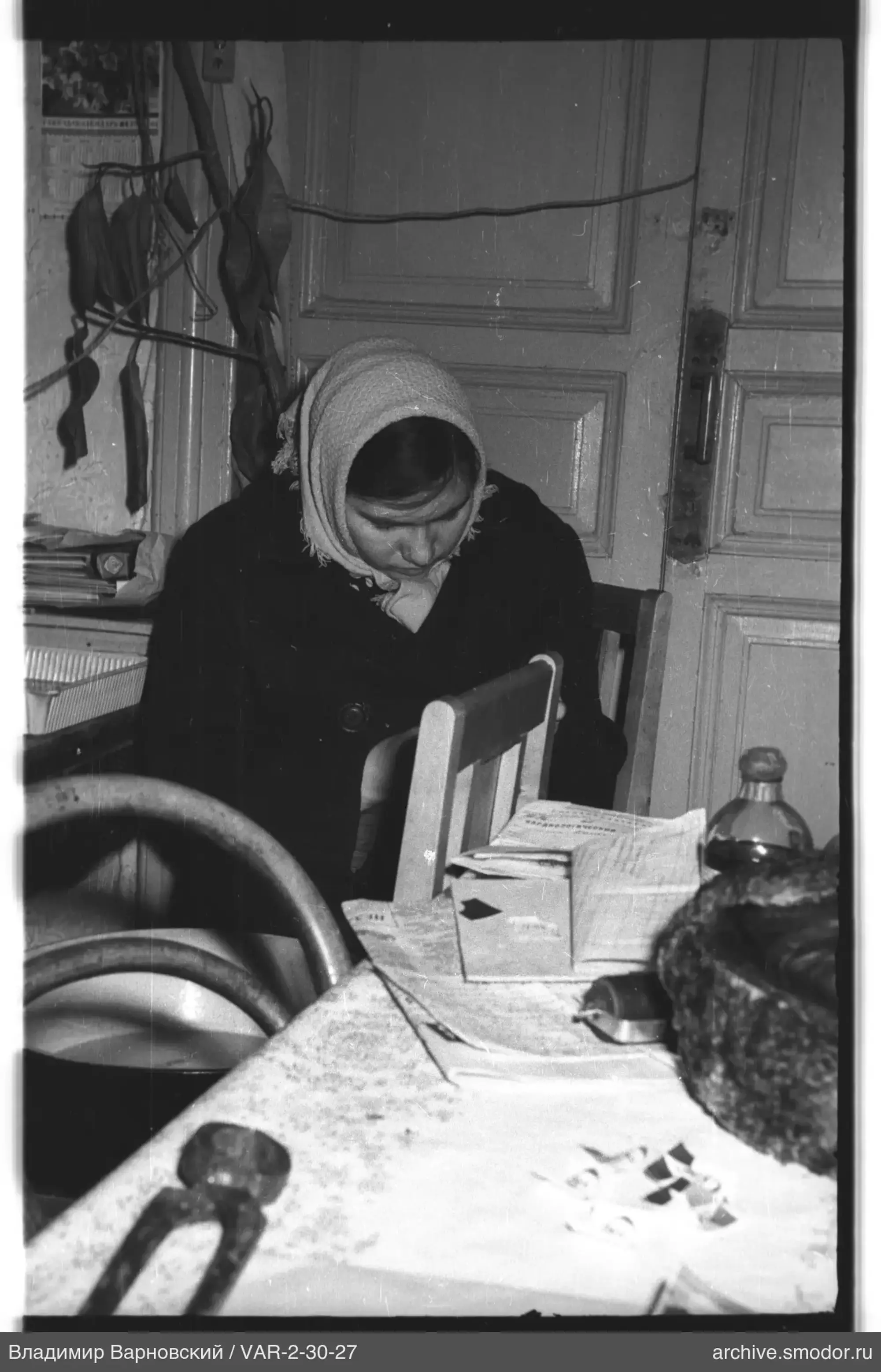 Woman sitting at a table with newspapers and plant