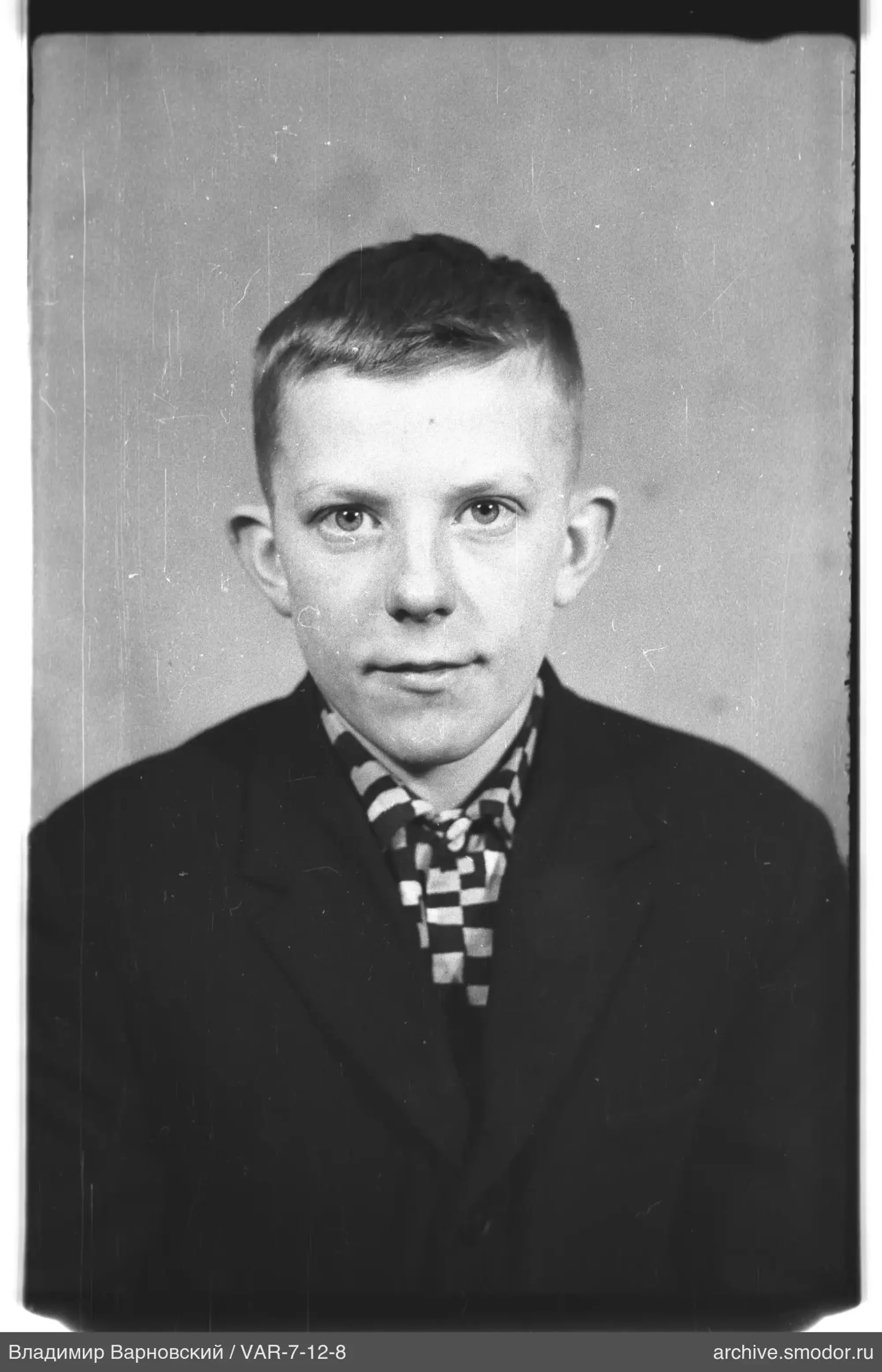 Porträt eines Jungen mit dunkler Jacke und kariertem Schal