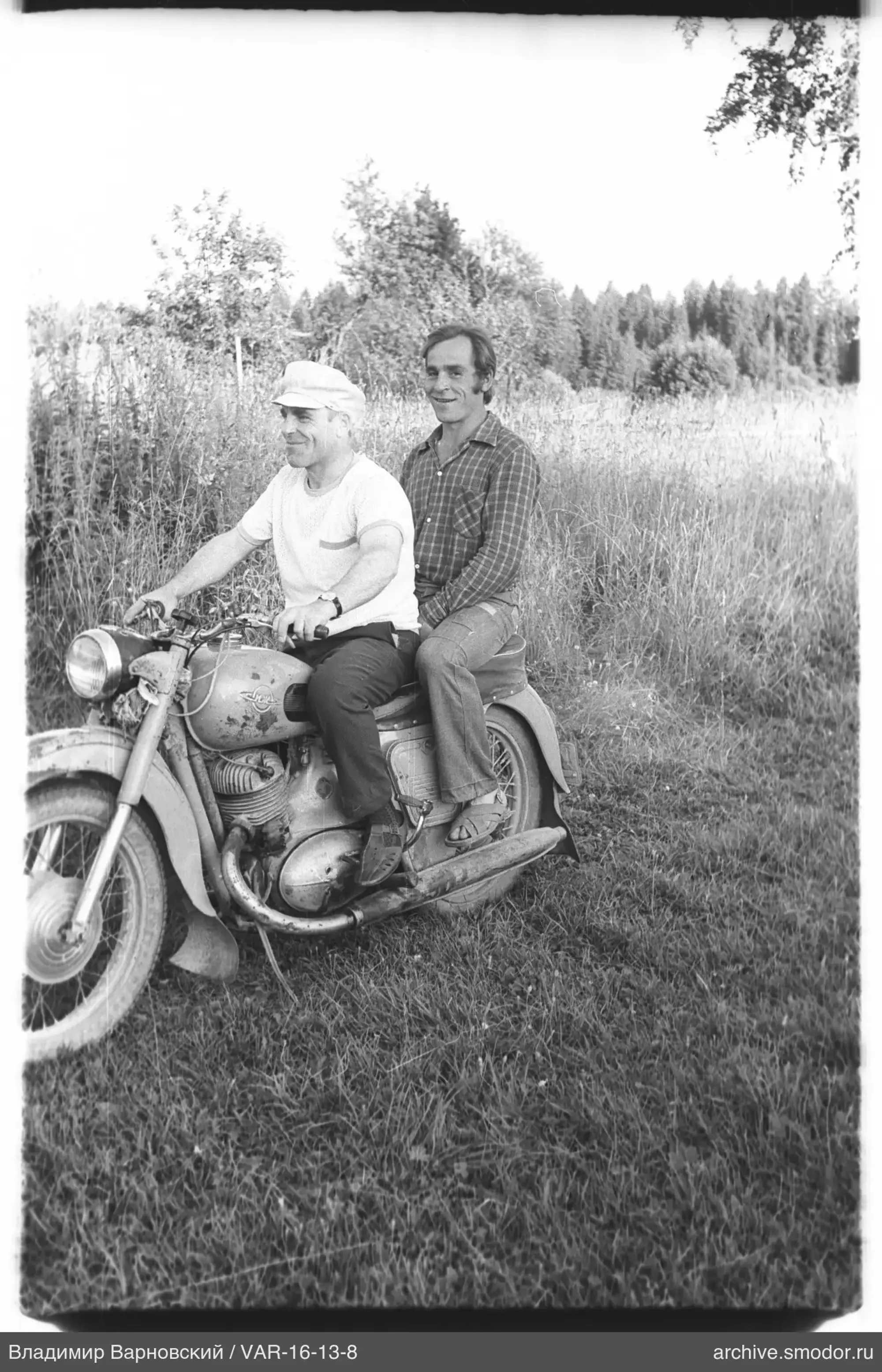 Zwei Männer auf einem Motorrad im Gras