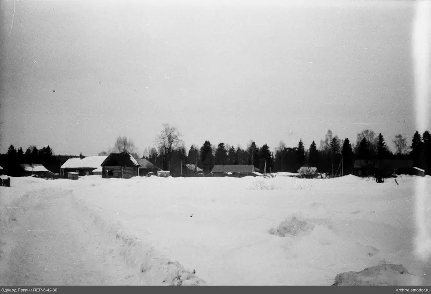 Schneebedecktes Feld und Holzhäuser