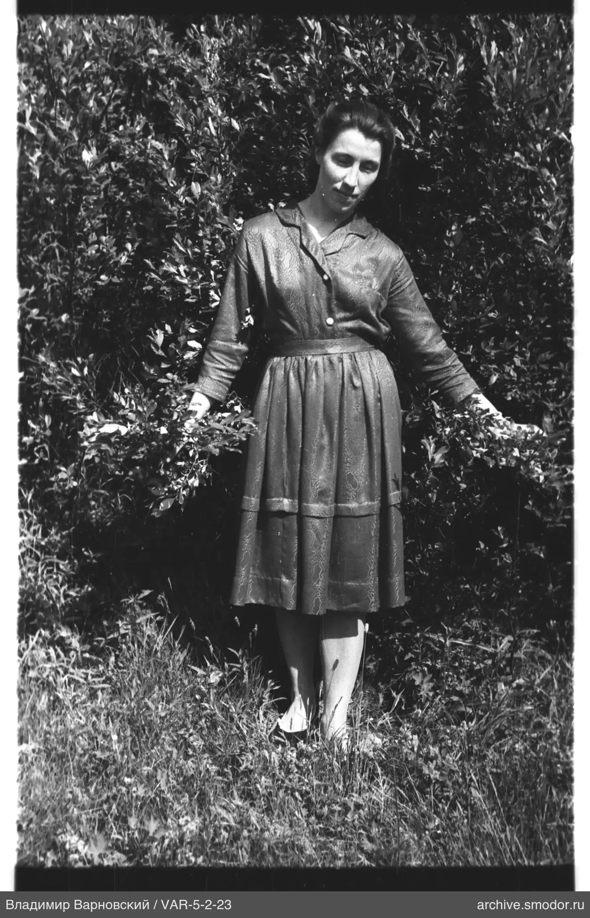Frau im Kleid auf Gras vor Büschen
