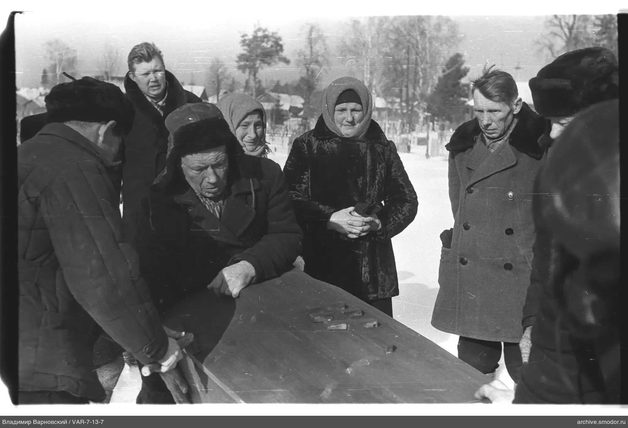 Группа людей у стола с игрой в домино