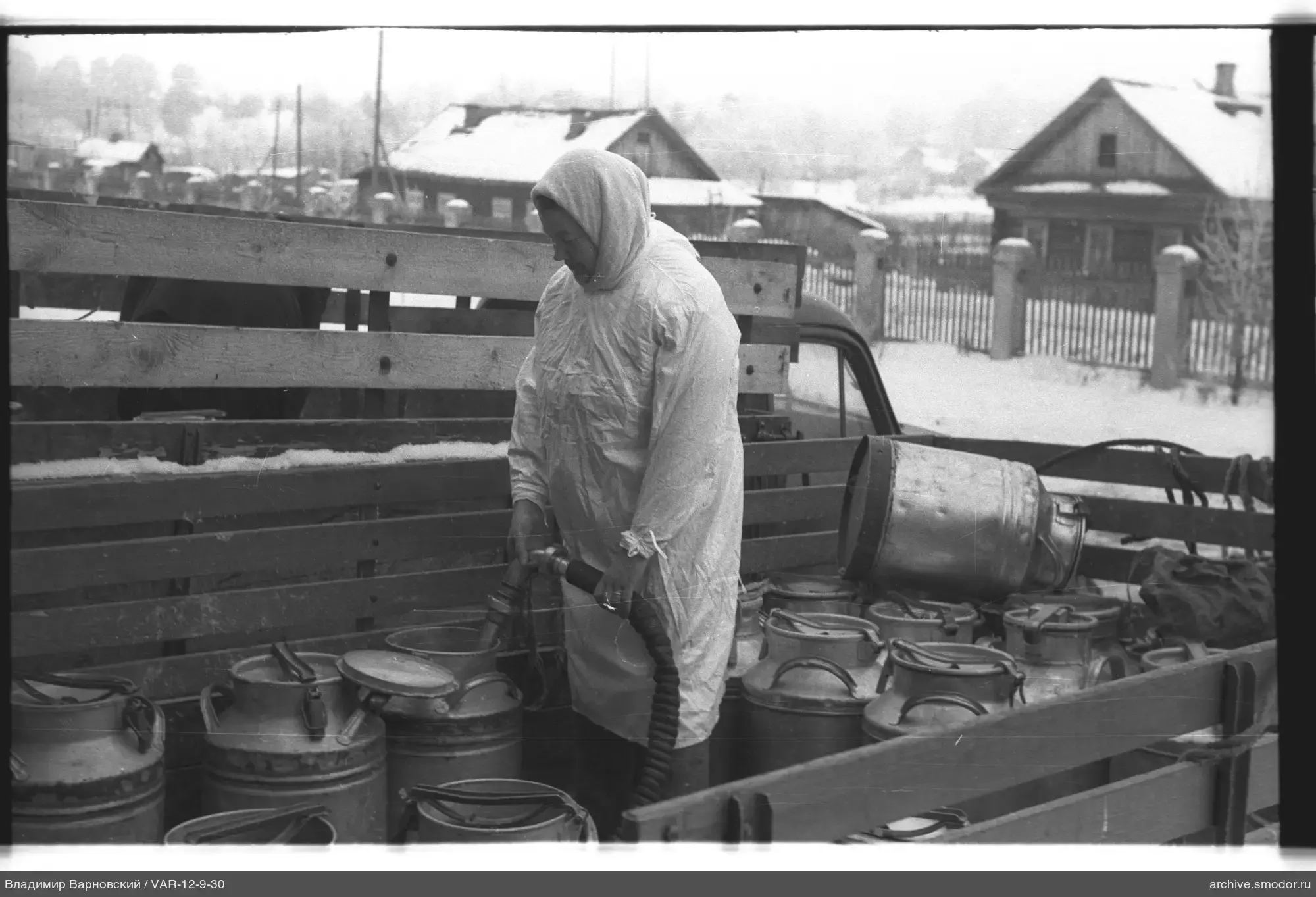Woman with hose in truck bed with milk cans