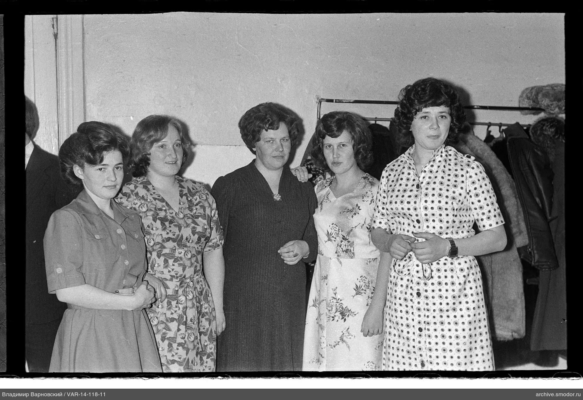 Group portrait of women by wall with coat rack