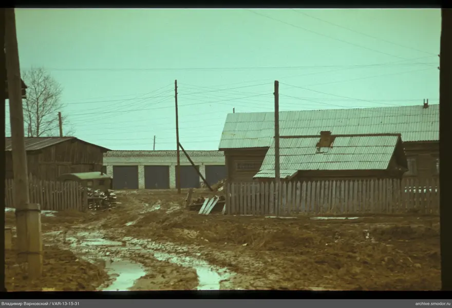 Dirt road with wooden fence and houses