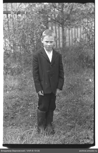 Junge auf Gras mit Gummistiefeln und Jacke