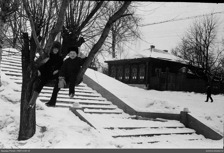 Zwei Kinder auf Baumzweigen bei schneebedeckter Treppe