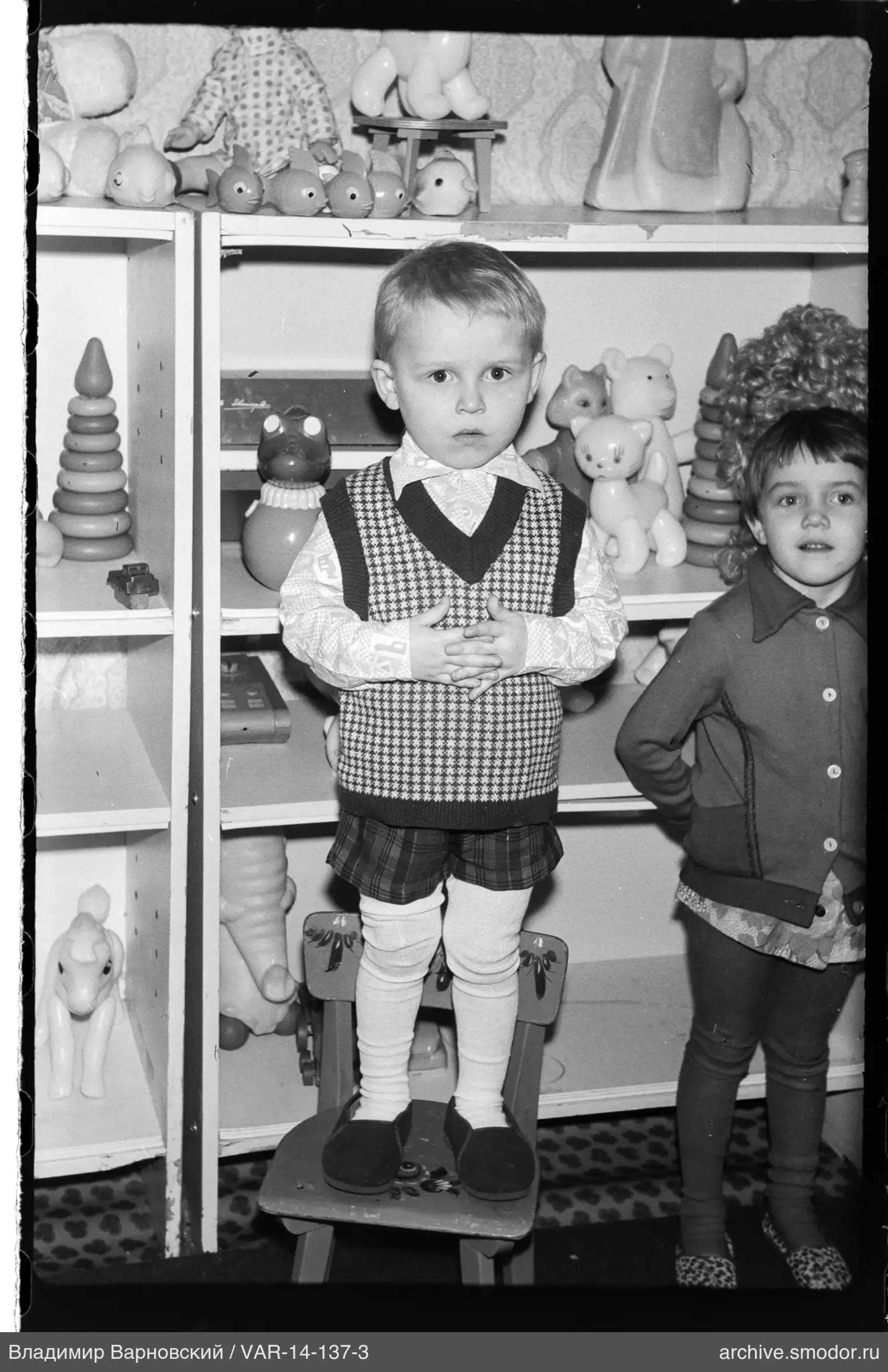 Two children with a toy shelf