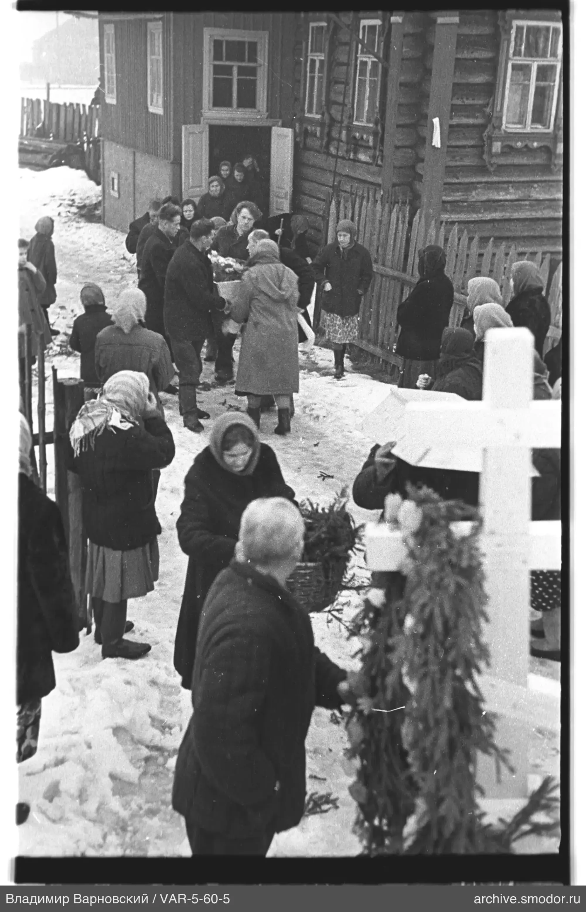 Beerdigungszug vor Holzhaus