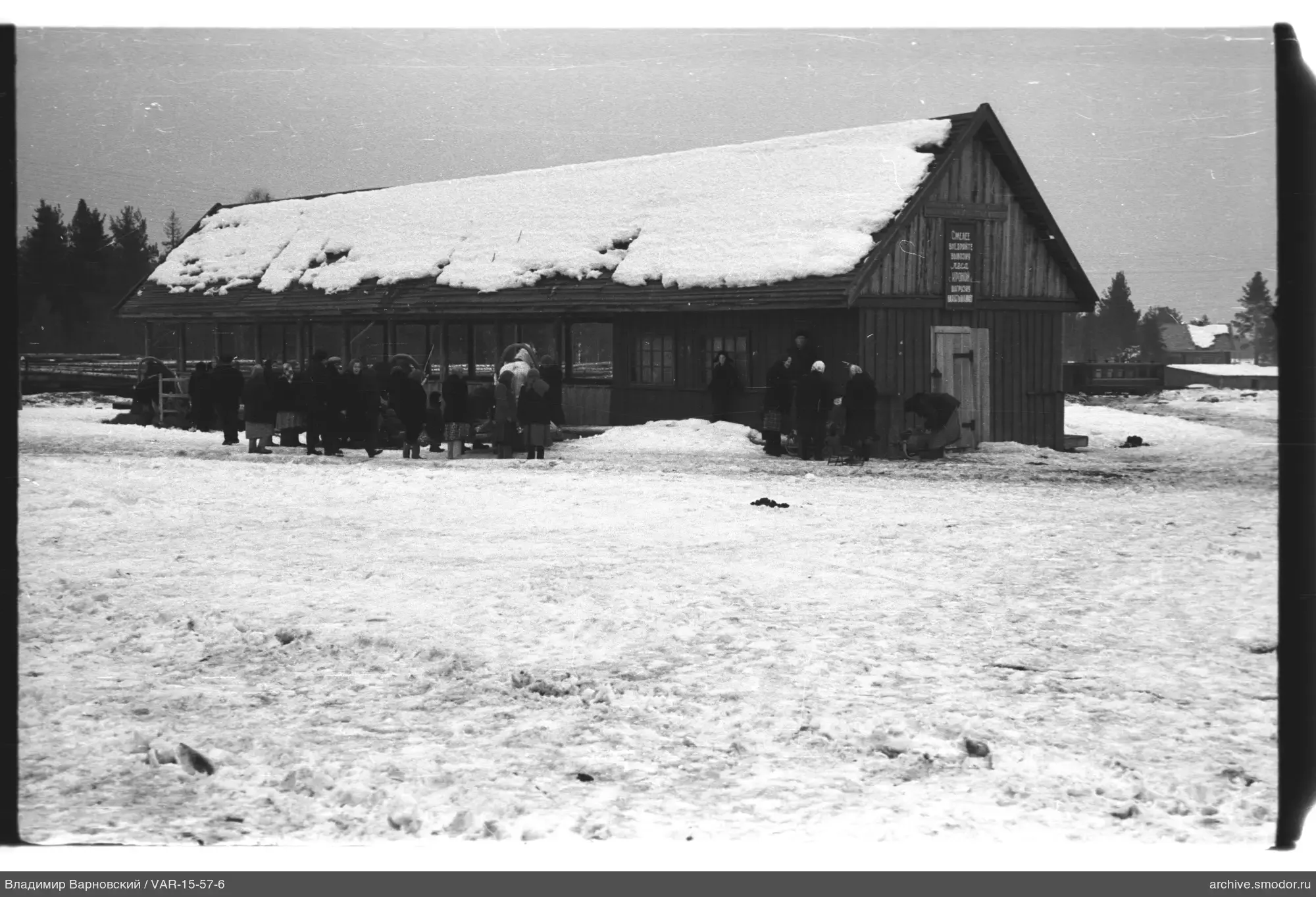 Gruppe von Menschen vor einem Holzgebäude im Schnee