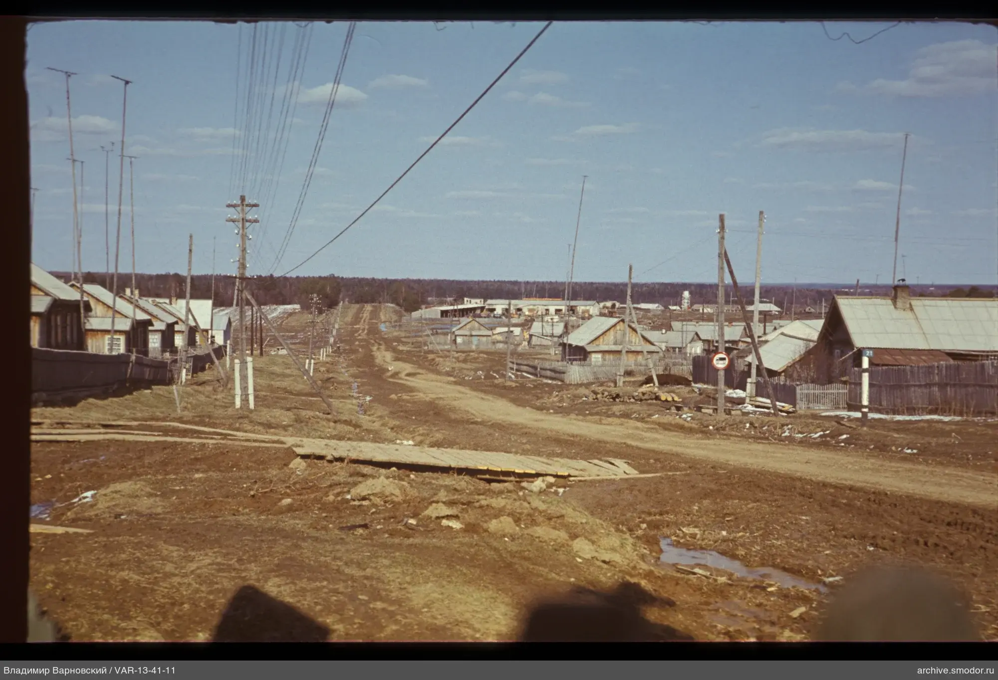 Village road with electric wires and forest